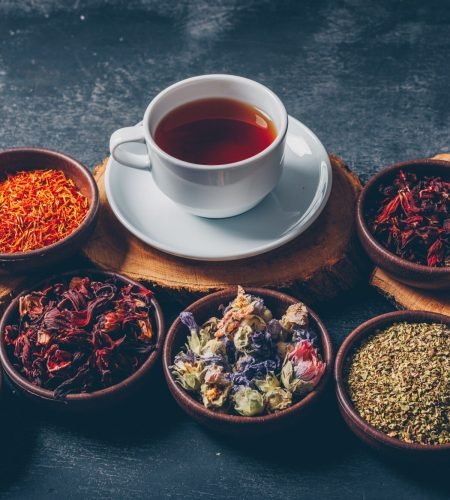 tea-herbs-bowls-with-wood-stubs-cup-tea-high-angle-view-dark-textured-background-space-text_176474-5178